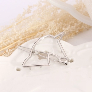 Detail of silver horse head hair clip with hollow outline design on a decorative plate