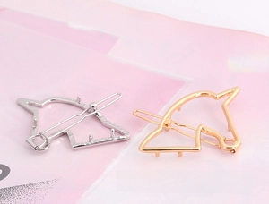 Detail view of unicorn-shaped metal hair clips in gold and silver with hollow design