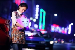Pink glowing star plush toy with LED lights and cute smiling face held by a woman