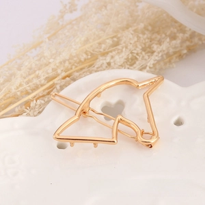 Close-up of a golden unicorn hair clip on a heart-shaped ceramic tray with dried flowers