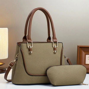 Detail of khaki woven tote bag with dark brown leather trim and golden metal hardware