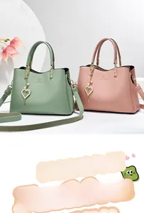 Close-up of leather handbag with heart pendant and adjustable strap in pastel colors