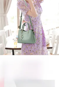 Close-up of mint green handbag with heart pearl pendant and adjustable shoulder strap