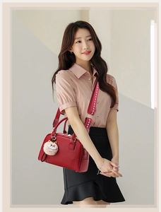 Detail of red litchi grain leather Boston bag featuring embroidered wide shoulder strap