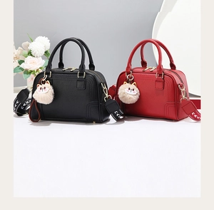 Detail view of black and red Boston handbags with floral wide straps and cat charms
