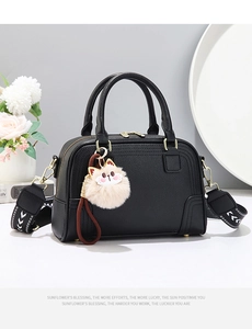 Detail of black leather Boston bag with gold hardware and geometric pattern shoulder strap
