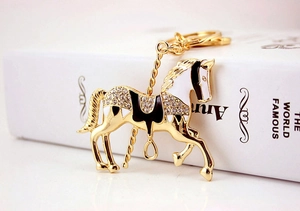 Vue macro du porte-clés cheval de manège doré orné de strass brillants et d'émail noir