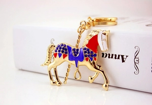 Gros plan du porte-clés carrousel doré avec émail bleu et strass scintillants