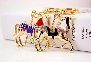 Détail de porte-clés cheval de manège dorés avec cristaux sur un livre ancien
