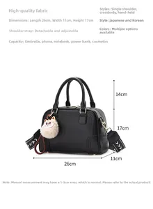 Detail of black lychee grain handbag with wide arrow strap and pink kitten charm
