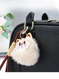 Close-up of cute cat plush charm on black pebbled leather handbag with woven lanyard