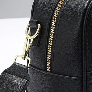 Close-up of black lychee grain leather handbag with premium gold zipper and metal hooks