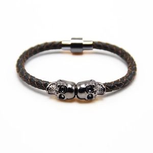Close-up of dual skulls and black braided leather on this punk magnetic bracelet