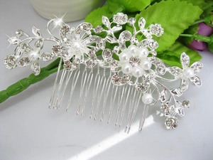 Close-up of silver bridal hair comb with rhinestone flowers and white pearls