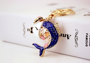 Detail of a golden koi fish keychain with blue enamel and sparkling pink crystal stones