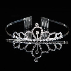 Detail of silver crown hair comb with sparkling rhinestones on black reflective surface
