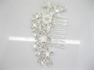 Close-up of silver bridal hair comb with elegant pearls, rhinestones and floral leaf motifs