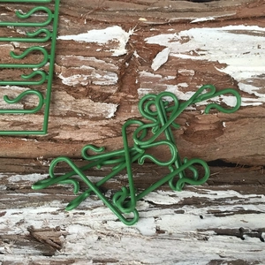 Detail of green S-shaped plastic Christmas hooks on tree bark background showing detachment