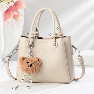 Minimalist beige pebble leather tote bag with a cute brown plush bear charm and strap