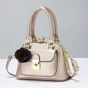Close-up of champagne gold shell bag with crystal clasp and 3D rose ornament detail