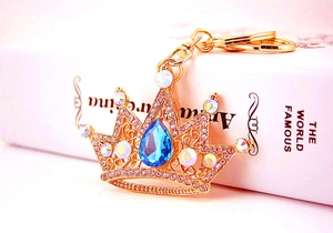 Detailed view of crown keychain with blue teardrop gemstone and gold filigree