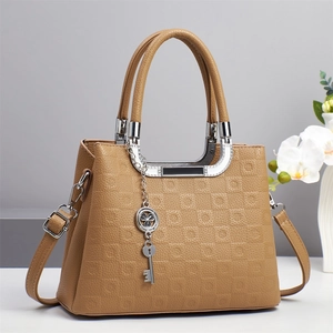Détail de la texture gaufrée et du pendentif clé argenté sur le sac à main en cuir kaki