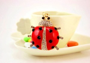 Close-up of a ladybug keychain with red enamel and rhinestones on a heart-shaped cup