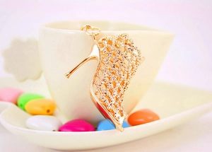 Close-up of golden metal hollow high heel keychain with intricate mesh design details