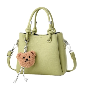 Minimalist avocado green shoulder bag with cute brown bear charm and knot handle detail