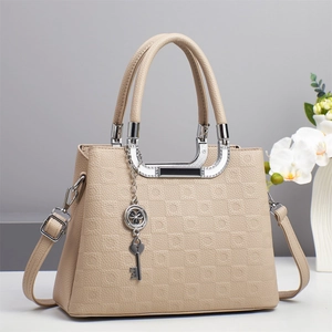 Détail du sac à main beige texture litchi avec breloque trèfle et finitions argentées