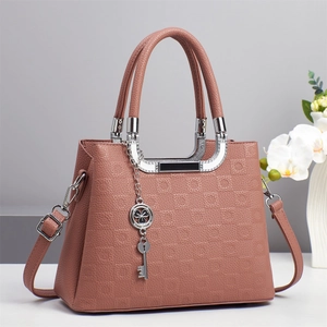 Sac à main rose gaufré élégant avec poignées argentées et breloque clé sur socle