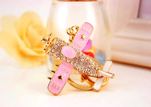 Detailed macro view of airplane keychain with pink enamel wings and sparkling rhinestones
