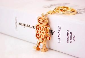 Detailed macro view of a golden metal robot keychain with rhinestone accents on a book