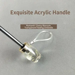 Transparent folding umbrella with an acrylic handle featuring gold sequins and clear wrist strap