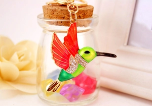 Detail of red and green hummingbird keychain with crystal accents on a glass jar