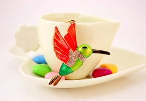Detailed hummingbird charm with colorful enamel and sparkling rhinestones on a heart cup