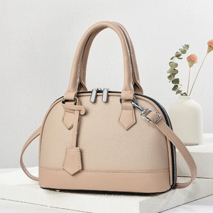 Elegant macaron beige shell handbag in litchi textured leather on a stone pedestal