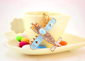 Close-up of golden helicopter keychain with sparkling crystals and blue enamel wings