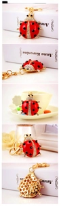 Macro details of red enamel ladybug keychain with white rhinestones and gold ring