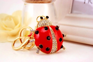 Detail of red ladybug keychain featuring gold metal base and sparkling white rhinestones