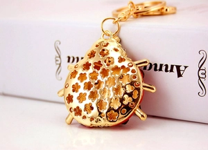 Detailed close-up of golden ladybug keychain featuring intricate hollowed flower patterns