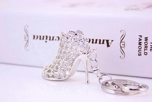 Macro detail of a silver hollow grid high heel shoe keychain with metal ring and chain