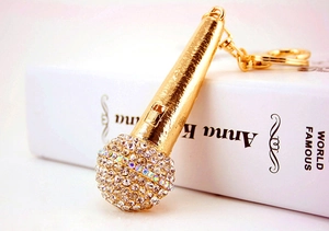 Detailed close-up of golden microphone keychain with crystal rhinestones on a white book
