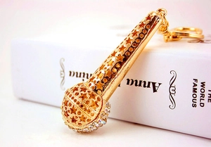 Macro detail of golden microphone keychain featuring hollow stars and crystal accents