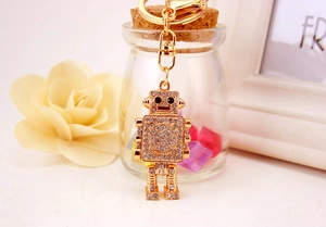 Macro shot of a golden robot keychain with sparkling rhinestones on a glass display