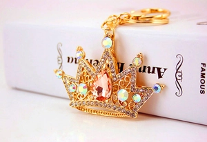 Detailed macro view of a golden crown keychain encrusted with crystals and a pink gemstone