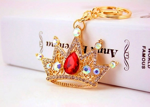 Close-up of golden crown keychain with red teardrop gem and sparkling rhinestones