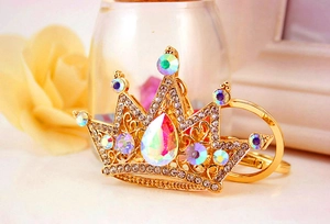 Macro detail of golden crown keychain with rhinestones and a large iridescent drop stone