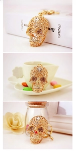 Detail of a gold skull keychain with crystal rhinestones and hollow floral carving