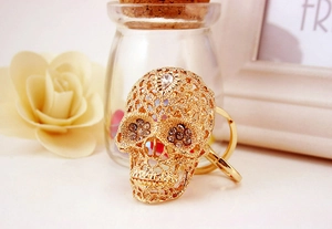 Detailed view of a gold skull keychain with crystal rhinestones on a white surface